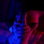 Nahaufnahme eines sinnlichen Moments zwischen zwei Personen bei einem Sextreffen in Köln, beleuchtet in verführerischem Blau- und Rotlicht.
